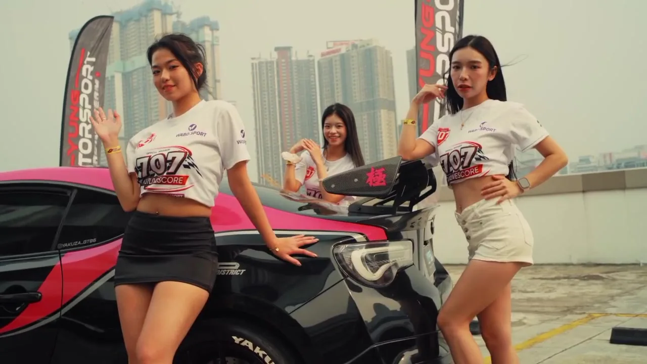 Models wearing 707Livescore shirts beside a pink-and-black modified car on the MyTown rooftop