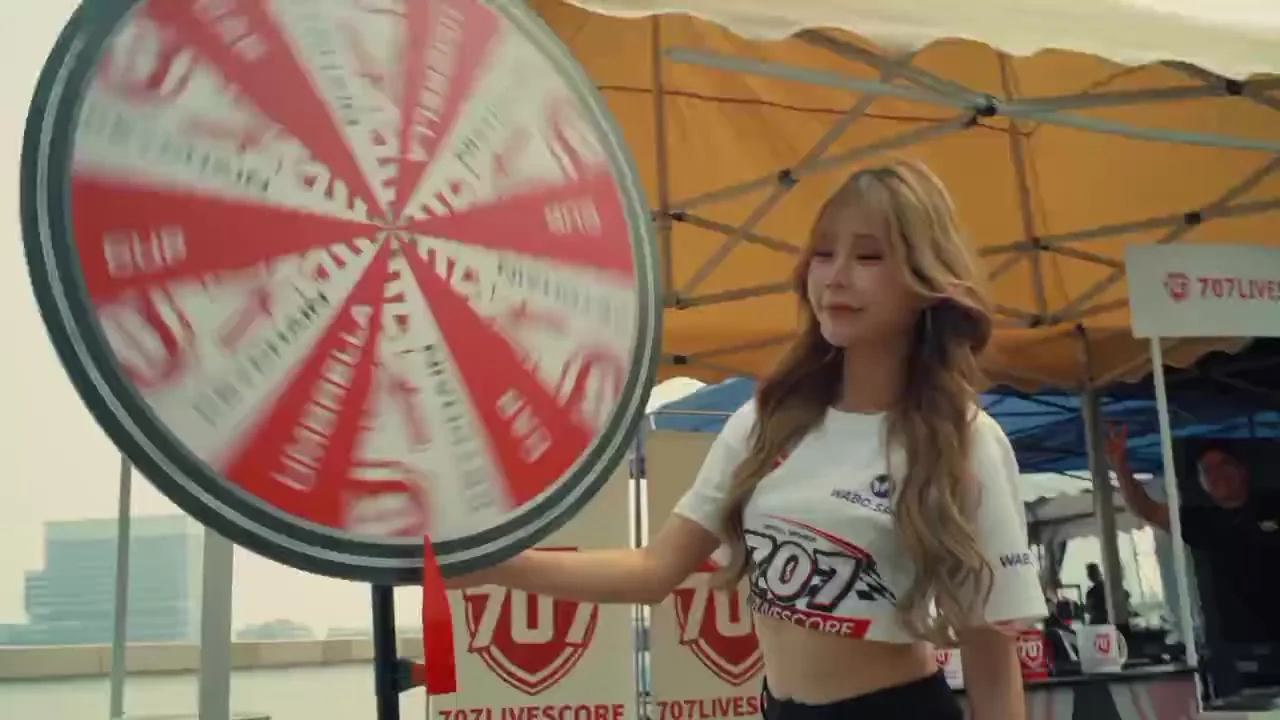 Red-and-white prize wheel spinning beside the 707Livescore booth under a yellow canopy